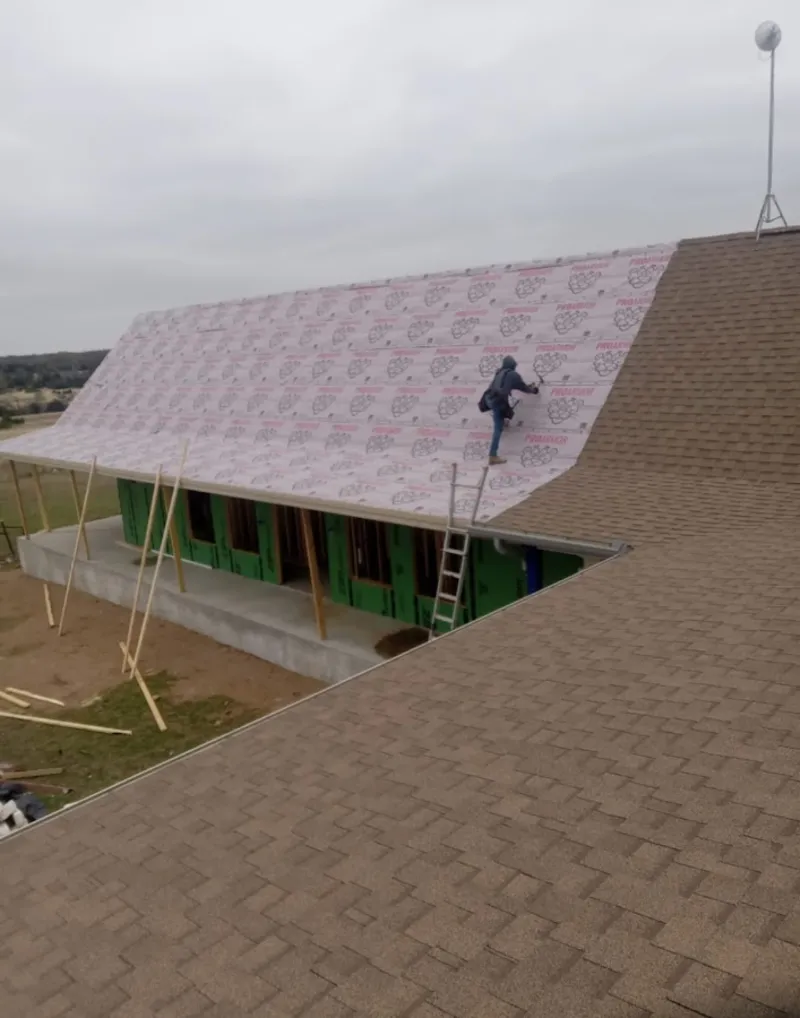 Worker preparing underlayment for a metal roof installation in Norwich